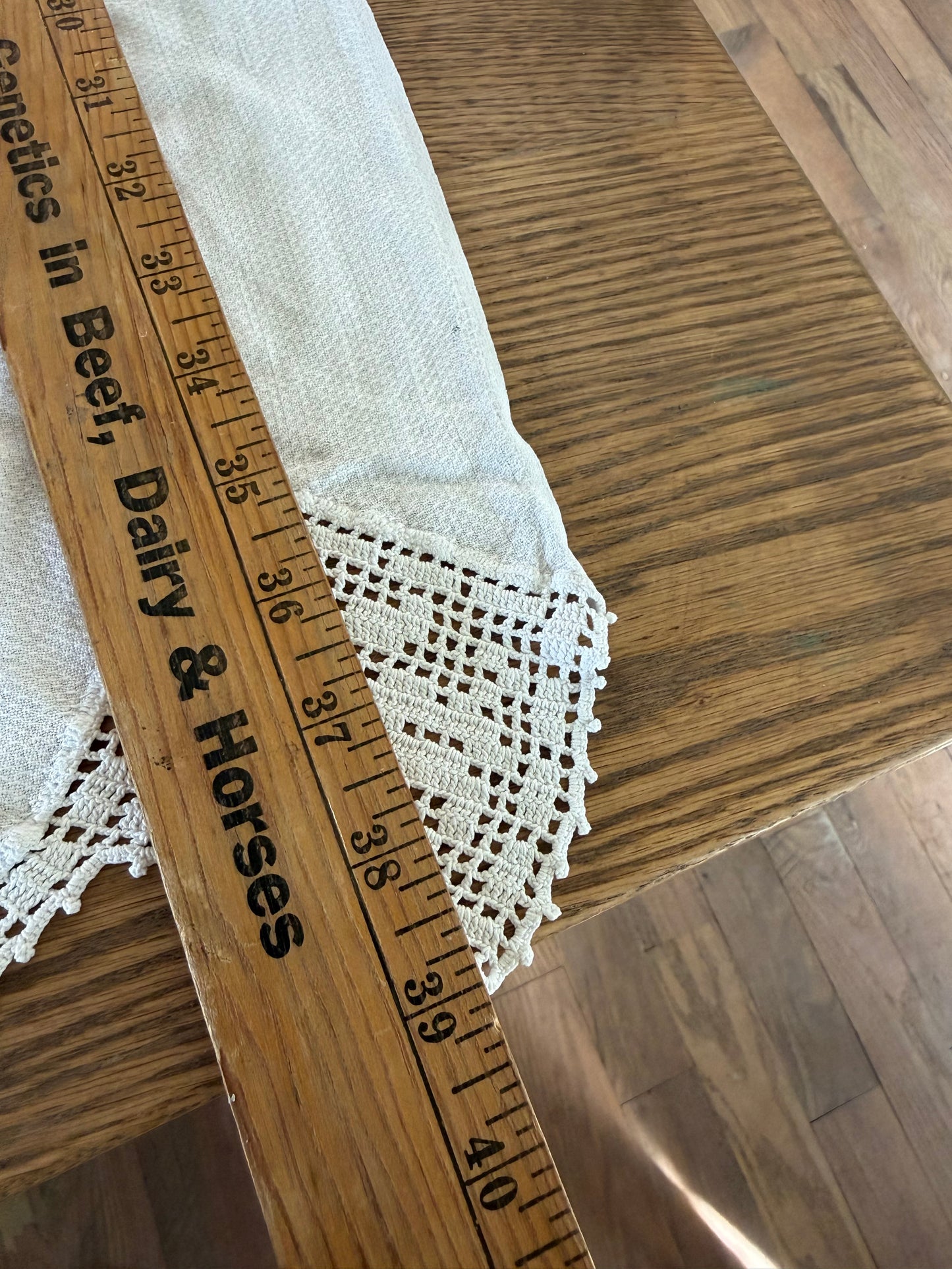 Vintage white linen table runner featuring hand-crocheted lace borders.