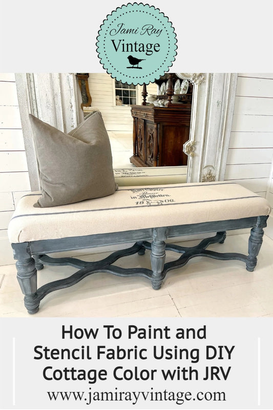 A bench is on the ground in front of a mirror and wall. There is a pillow decorating the top of the bench