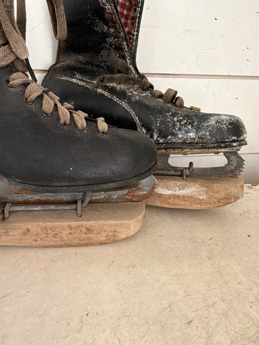 Set of black antique ice skates with wood guards