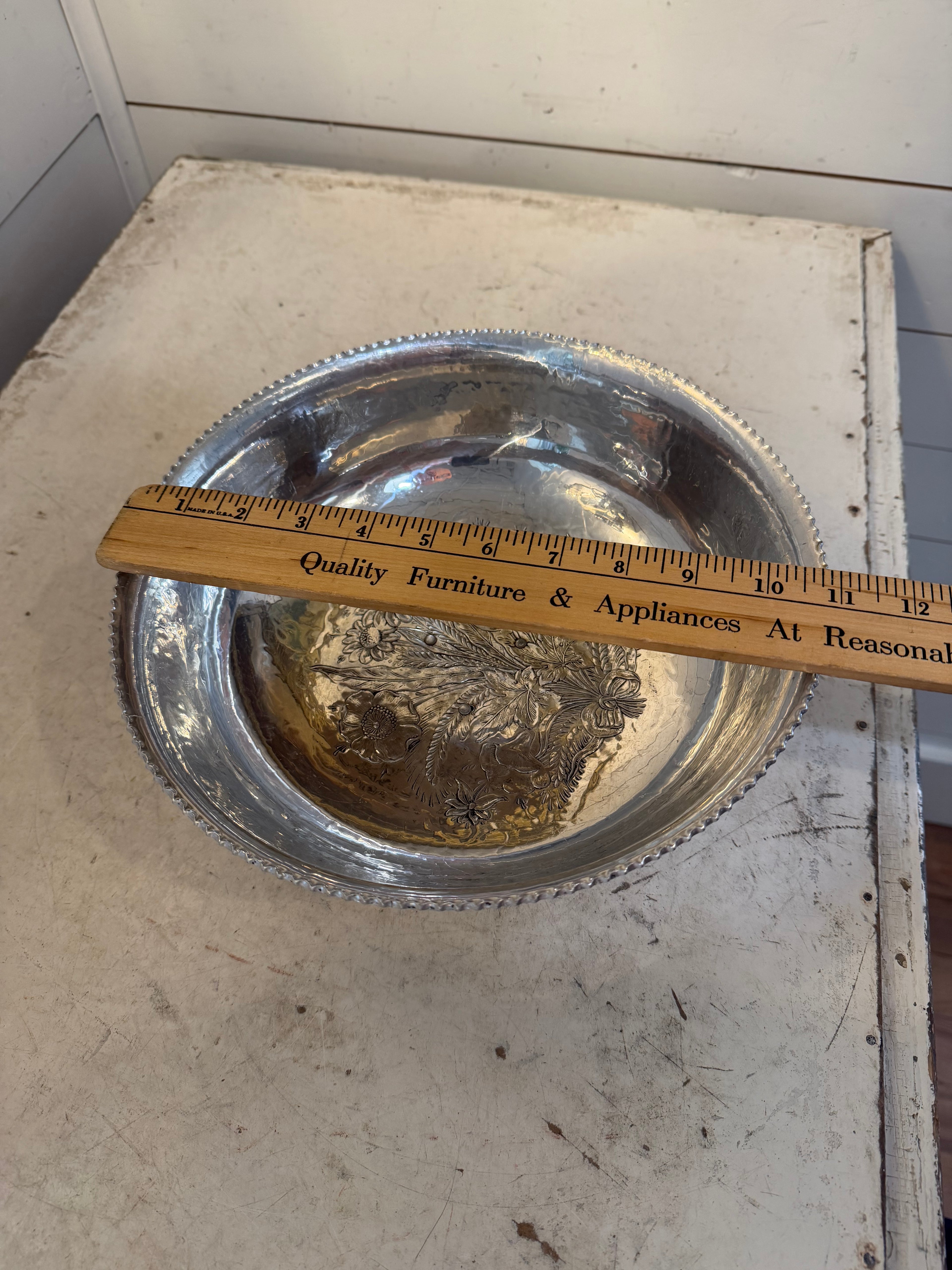 Vintage hand-wrought aluminum serving bowl with a floral design in the center and a scalloped rim
