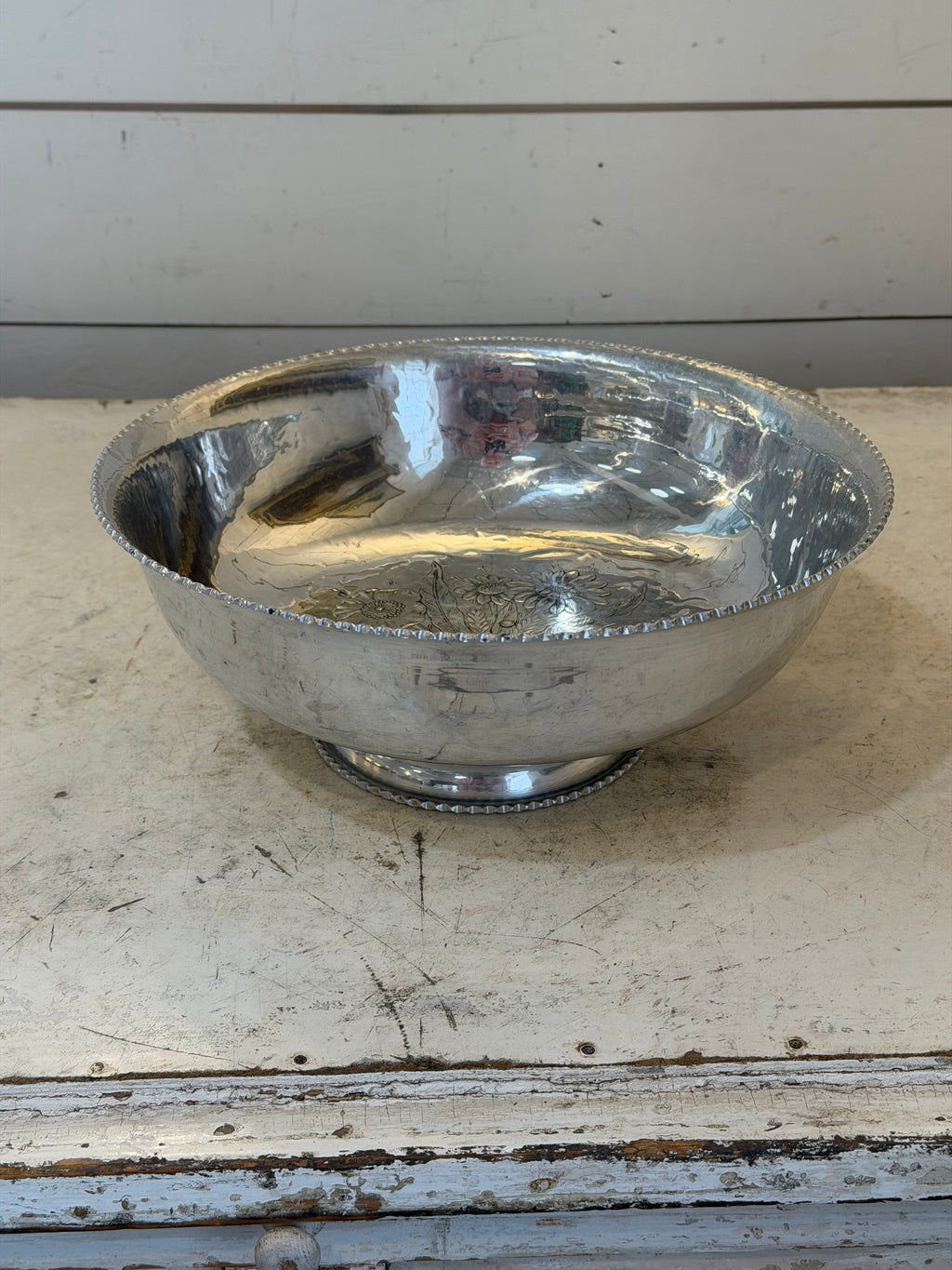 Vintage hand-wrought aluminum serving bowl with a floral design in the center and a scalloped rim