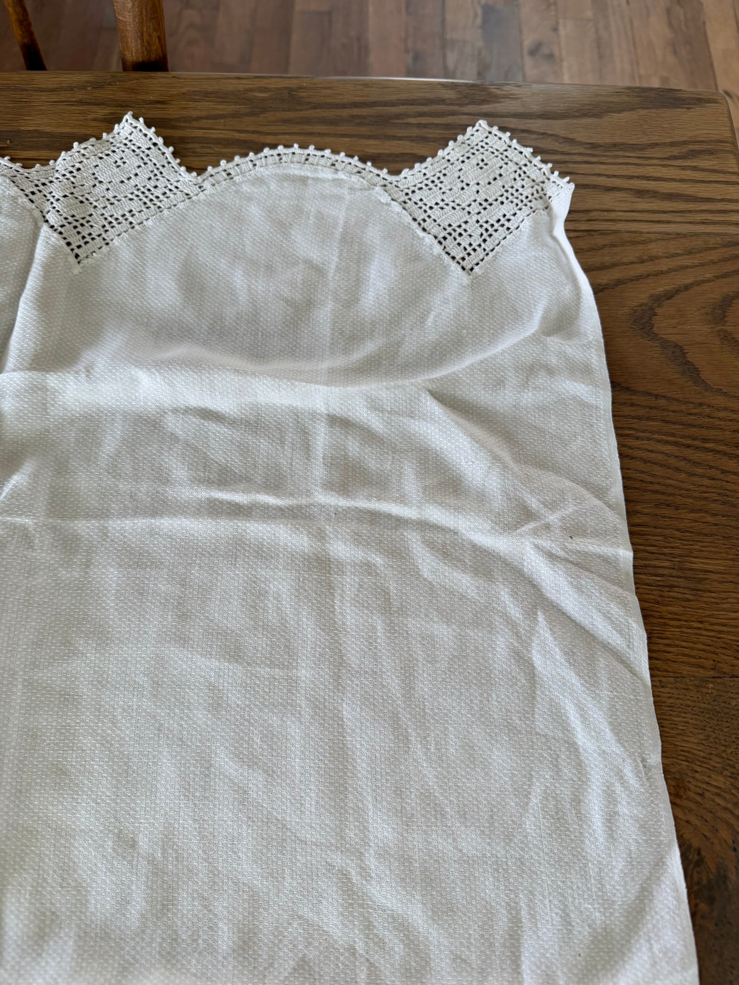 Vintage white linen table runner featuring hand-crocheted lace borders.