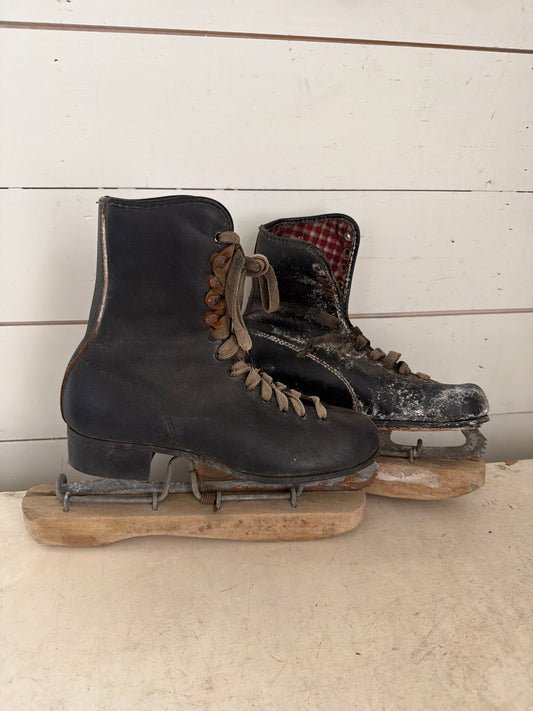 Set of black antique ice skates with wood guards