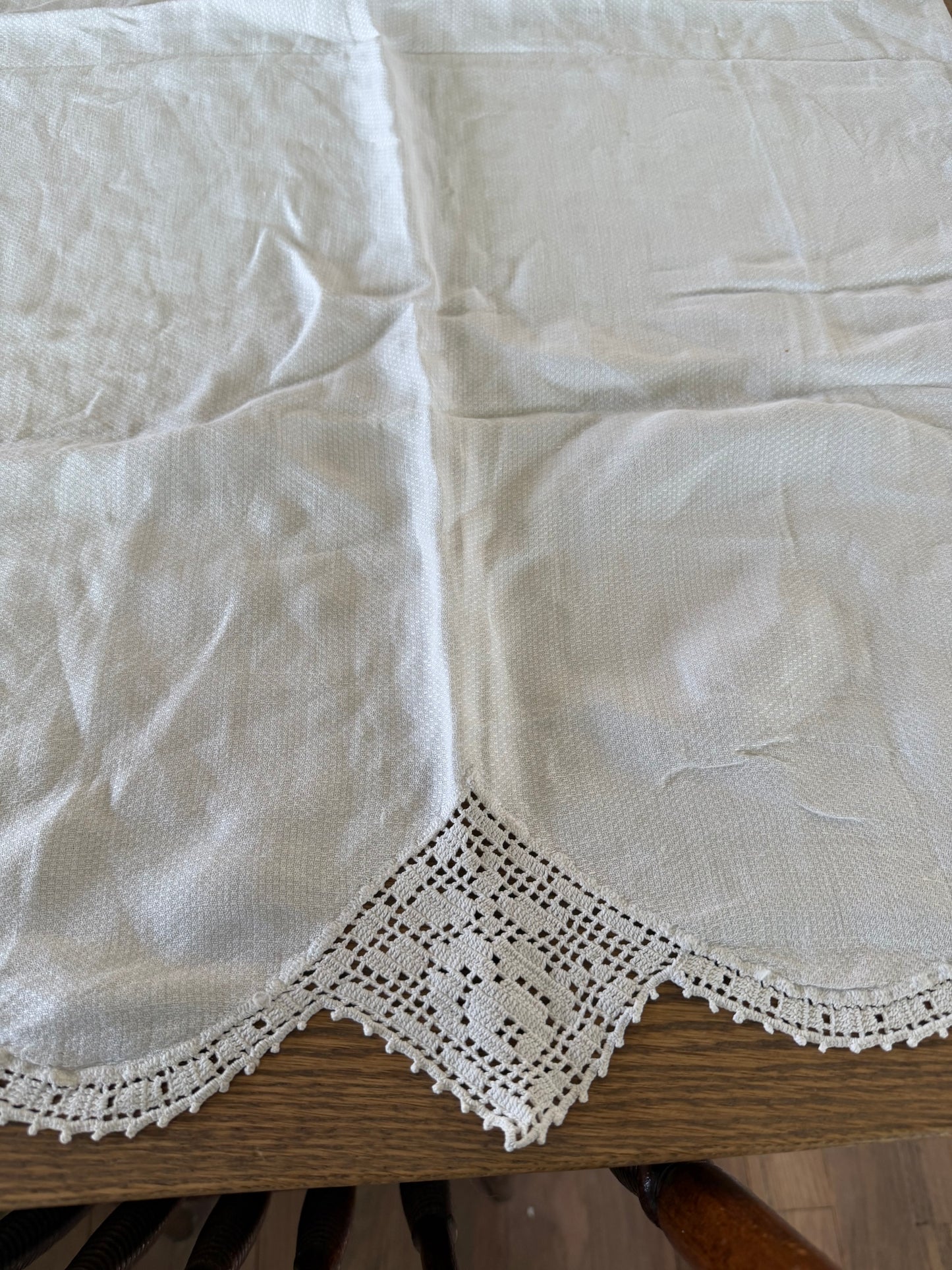 Vintage white linen table runner featuring hand-crocheted lace borders.