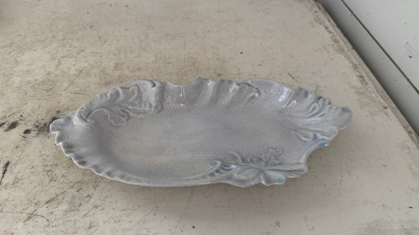 ceramic serving dish features a light blue glaze with a distinct crackle finish and ornate, raised leaf-like ruffles as is