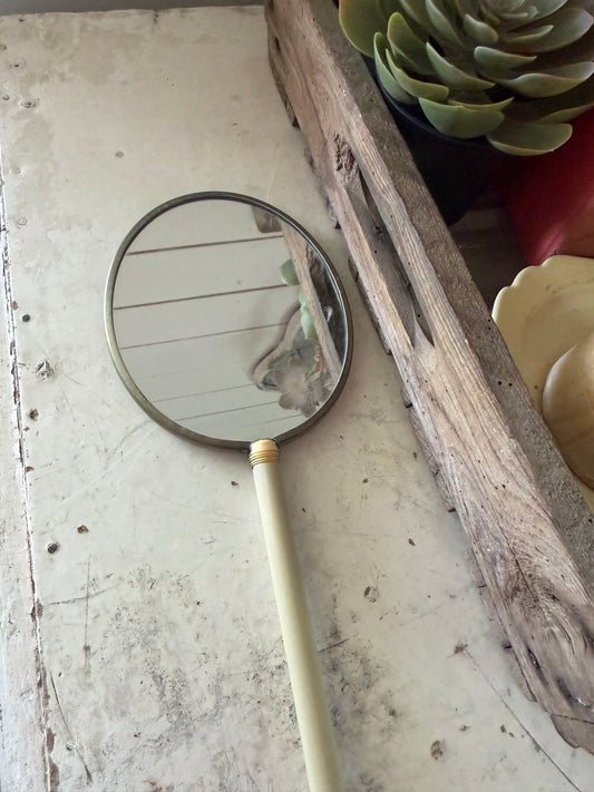 Art Nouveau style hand mirror with a yellow celluloid back and a long, slender handle