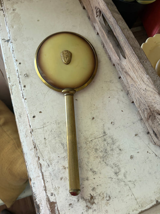 Art Nouveau style hand mirror with a yellow celluloid back and a long, slender handle