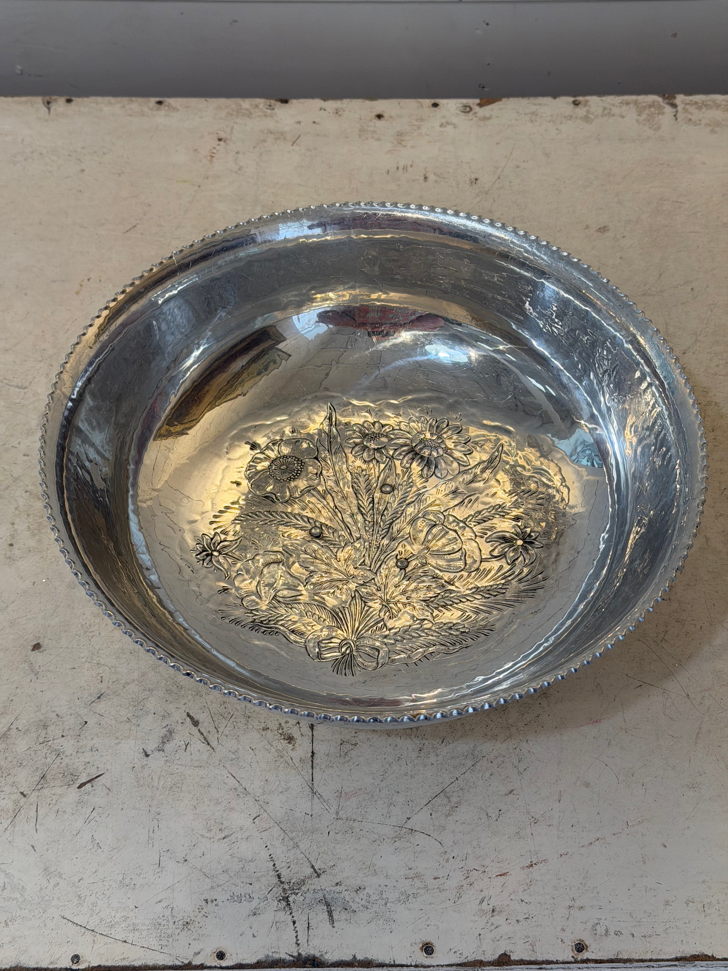Vintage hand-wrought aluminum serving bowl with a floral design in the center and a scalloped rim