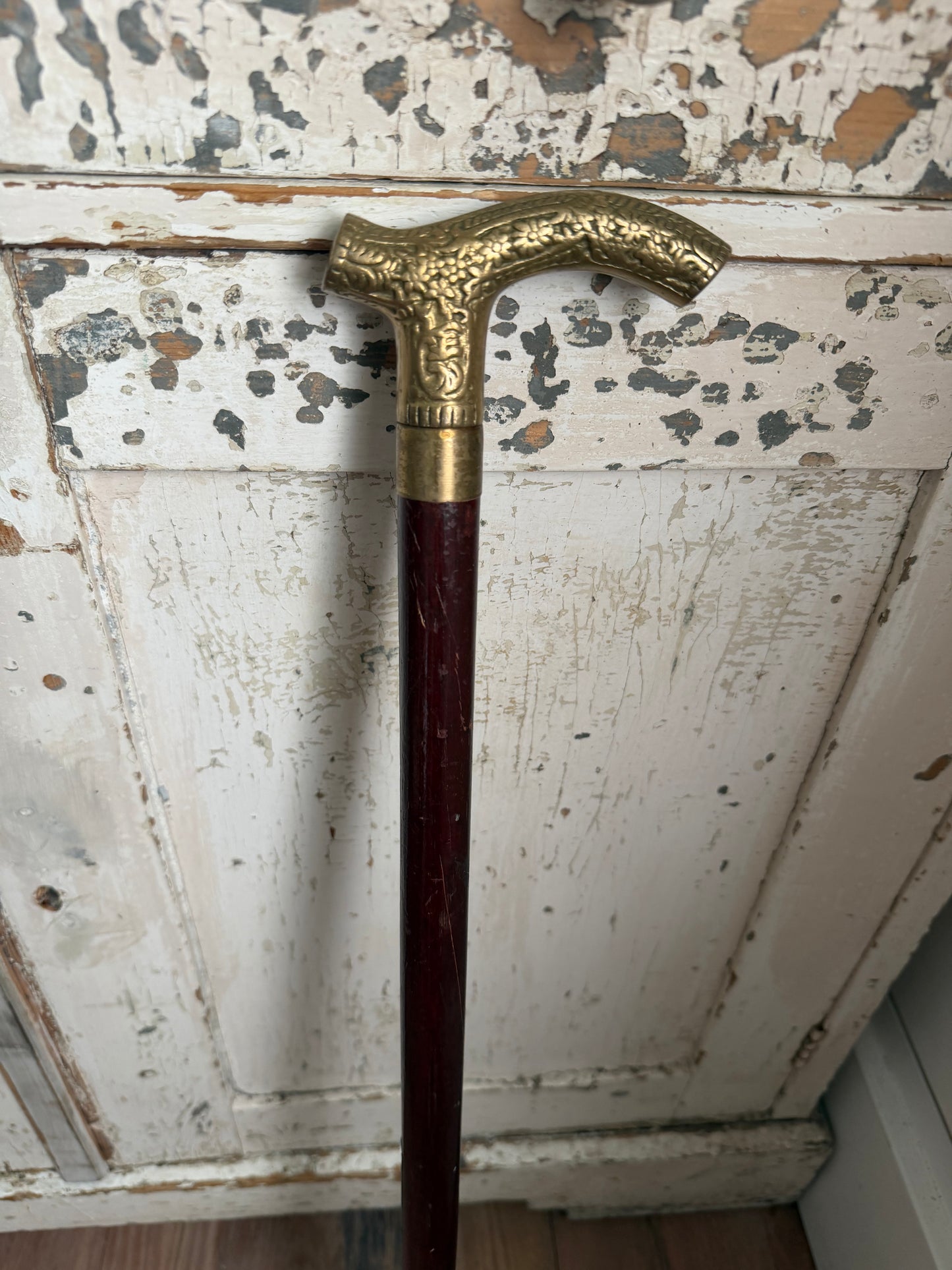 antique-style walking cane with a brass handle featuring an embossed pattern