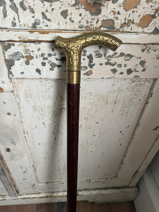 antique-style walking cane with a brass handle featuring an embossed pattern