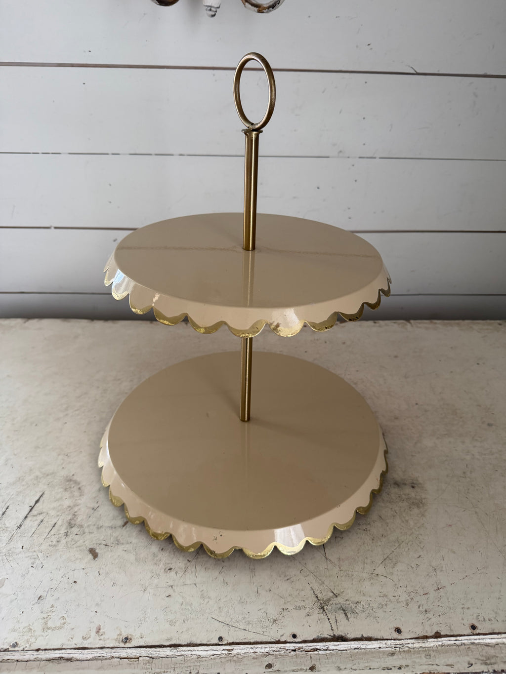 Two-tiered metal cake stand with a scalloped edge and a gold-tone finish