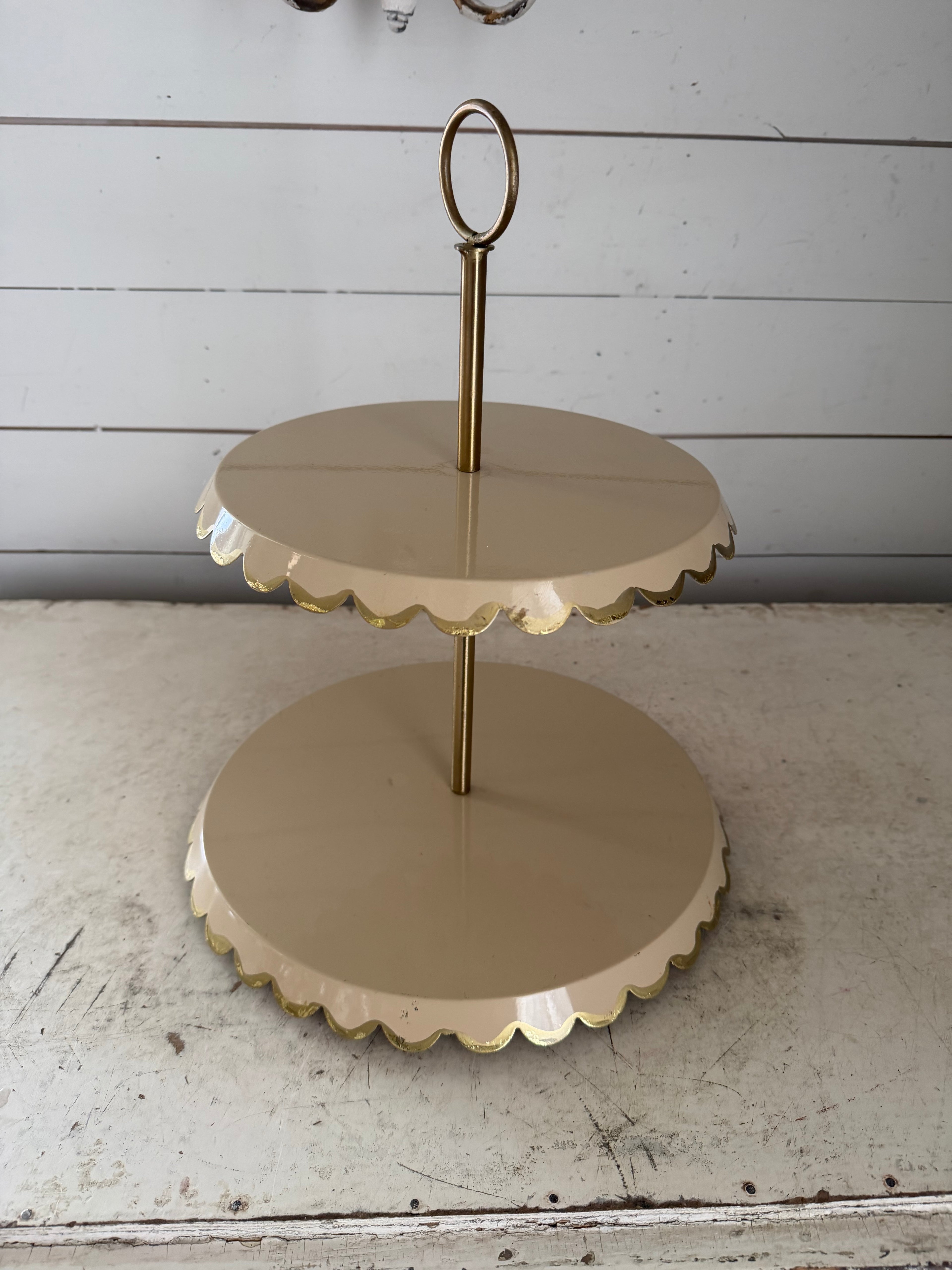 Two-tiered metal cake stand with a scalloped edge and a gold-tone finish