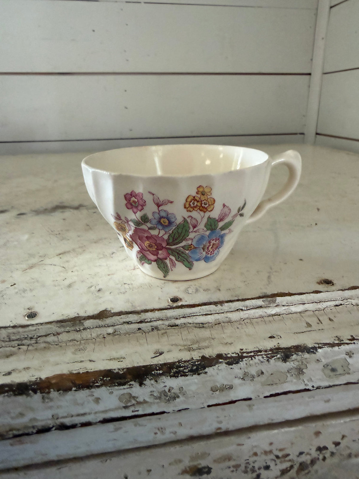 Vintage teacup in the "Romney" pattern, featuring a colorful floral design on a Gadroon-shaped white body
