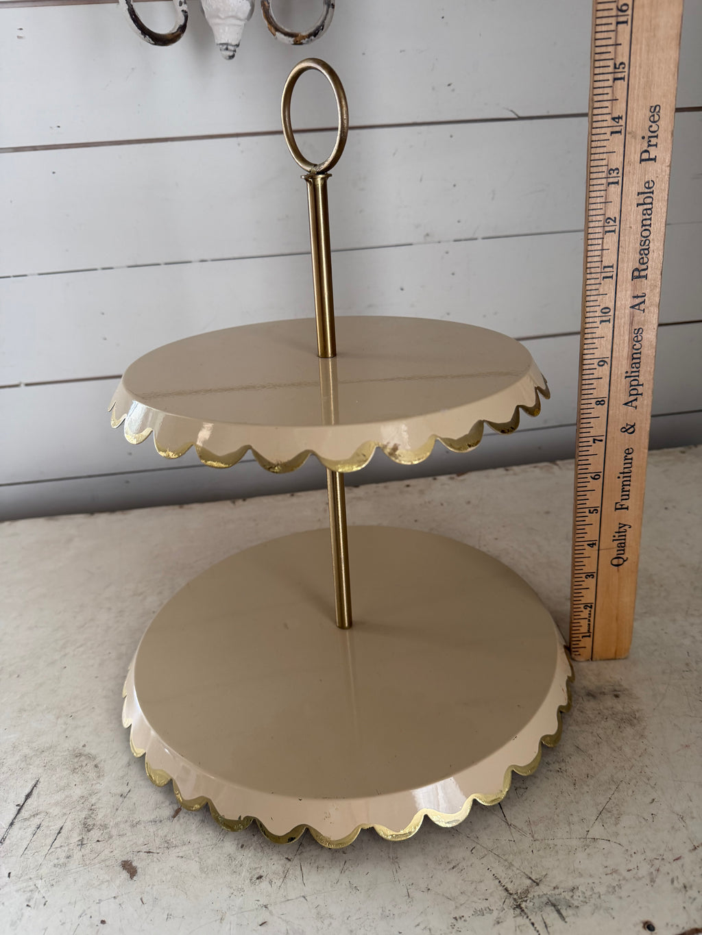 Two-tiered metal cake stand with a scalloped edge and a gold-tone finish