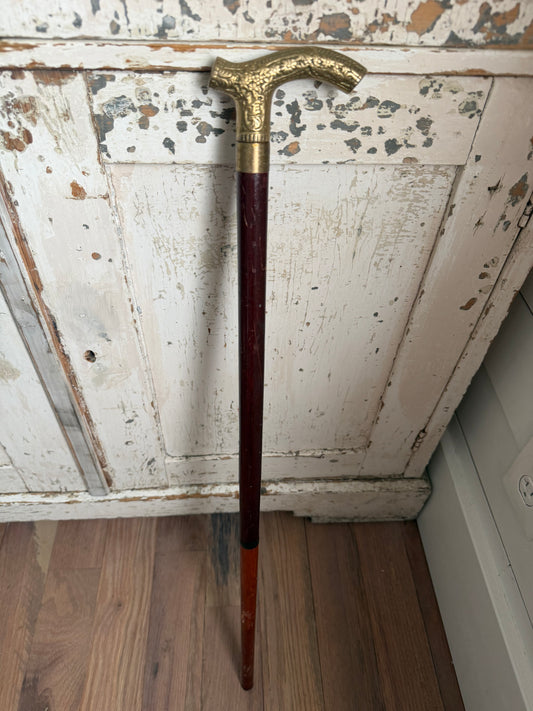 antique-style walking cane with a brass handle featuring an embossed pattern