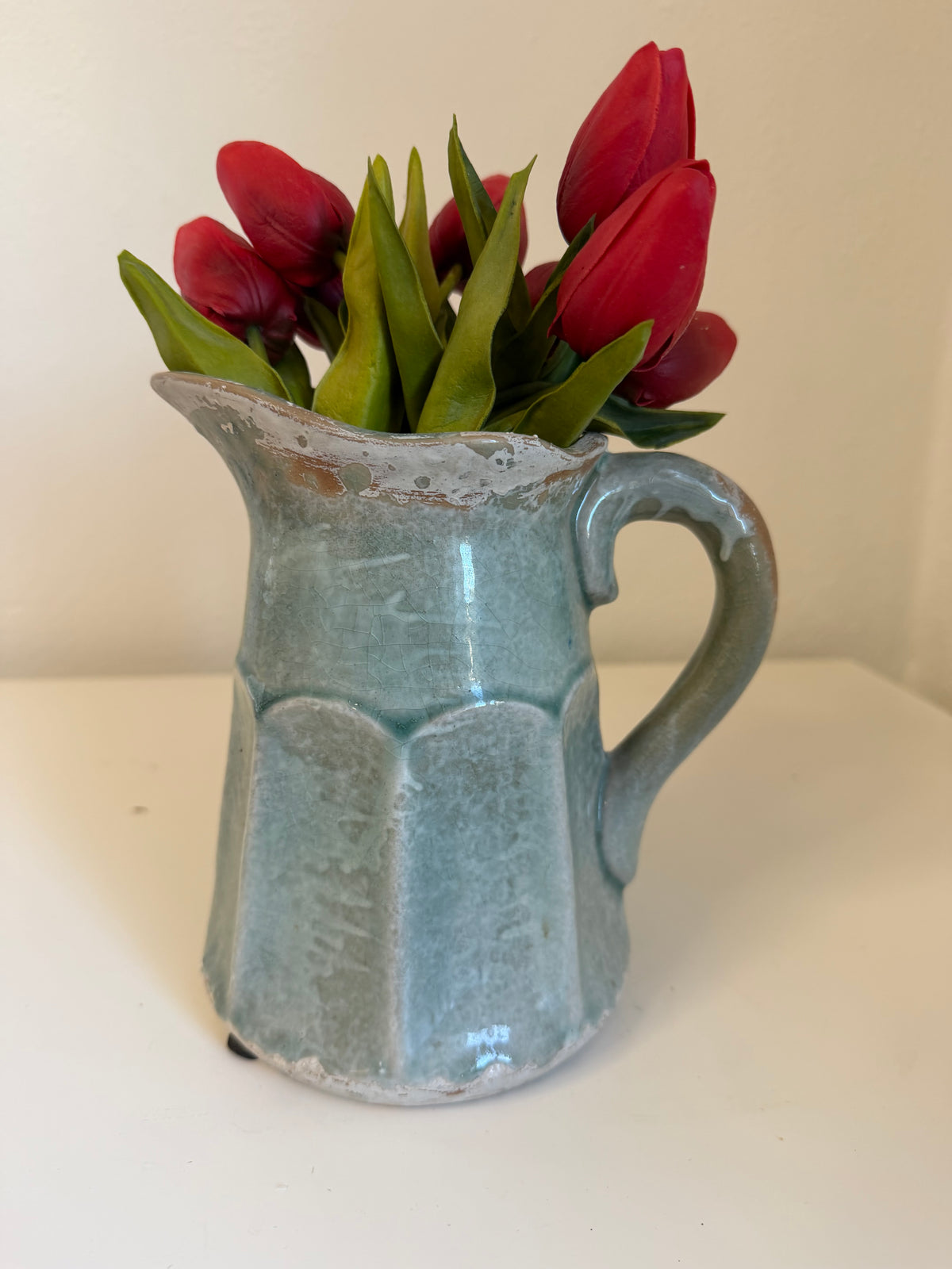 Ceramic pitcher with a faceted body, curved handle, and rustic crackle-glazed finish - tulips included