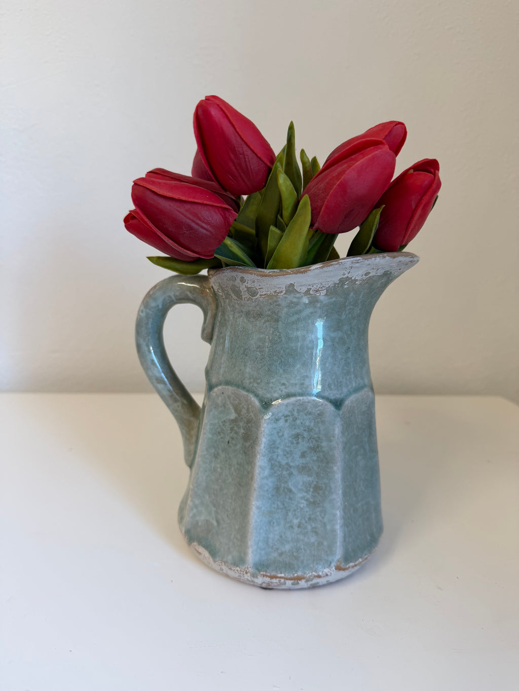 Ceramic pitcher with a faceted body, curved handle, and rustic crackle-glazed finish - tulips included