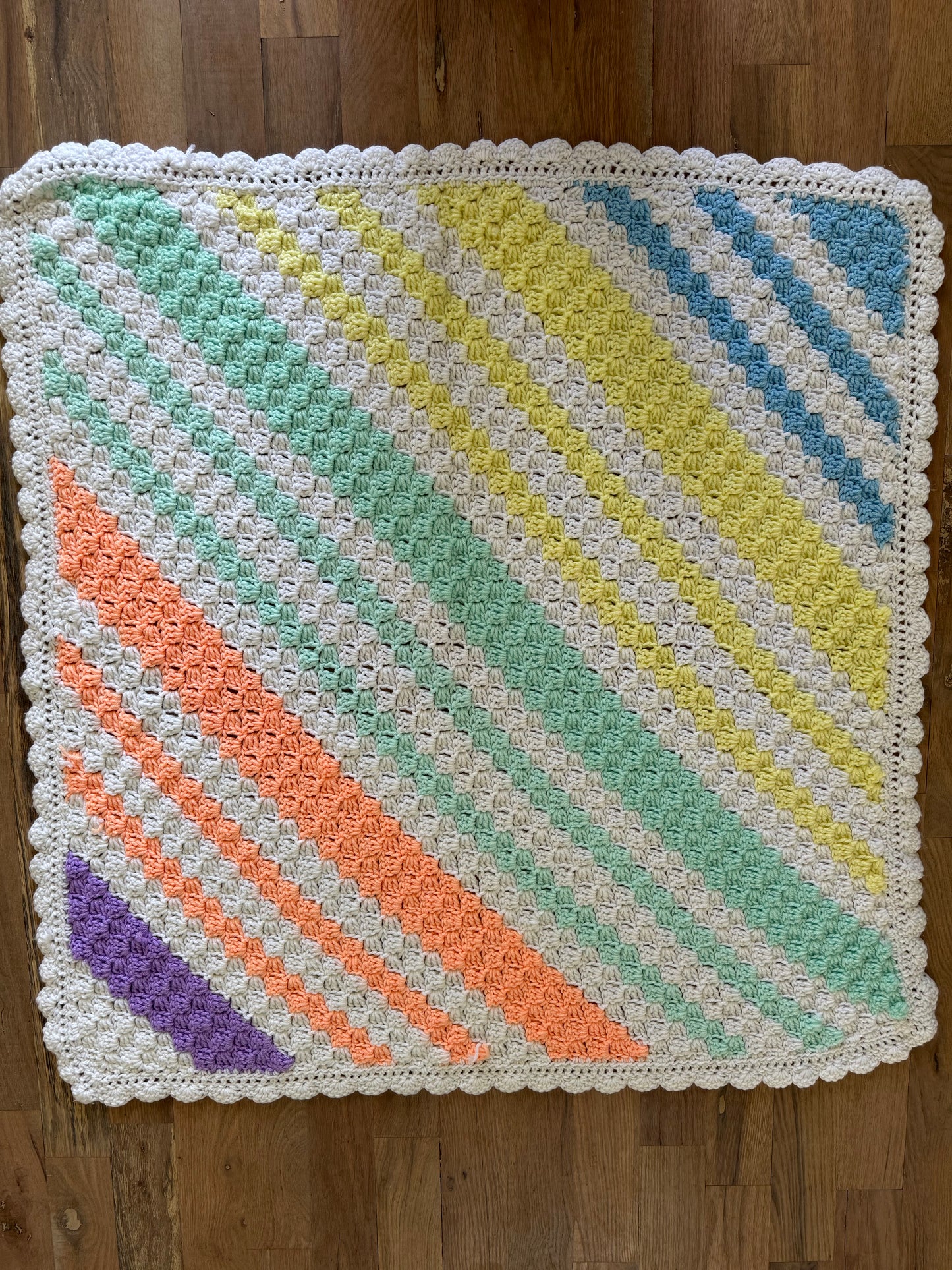 Peach, green, yellow, white, blue and purple striped afghan