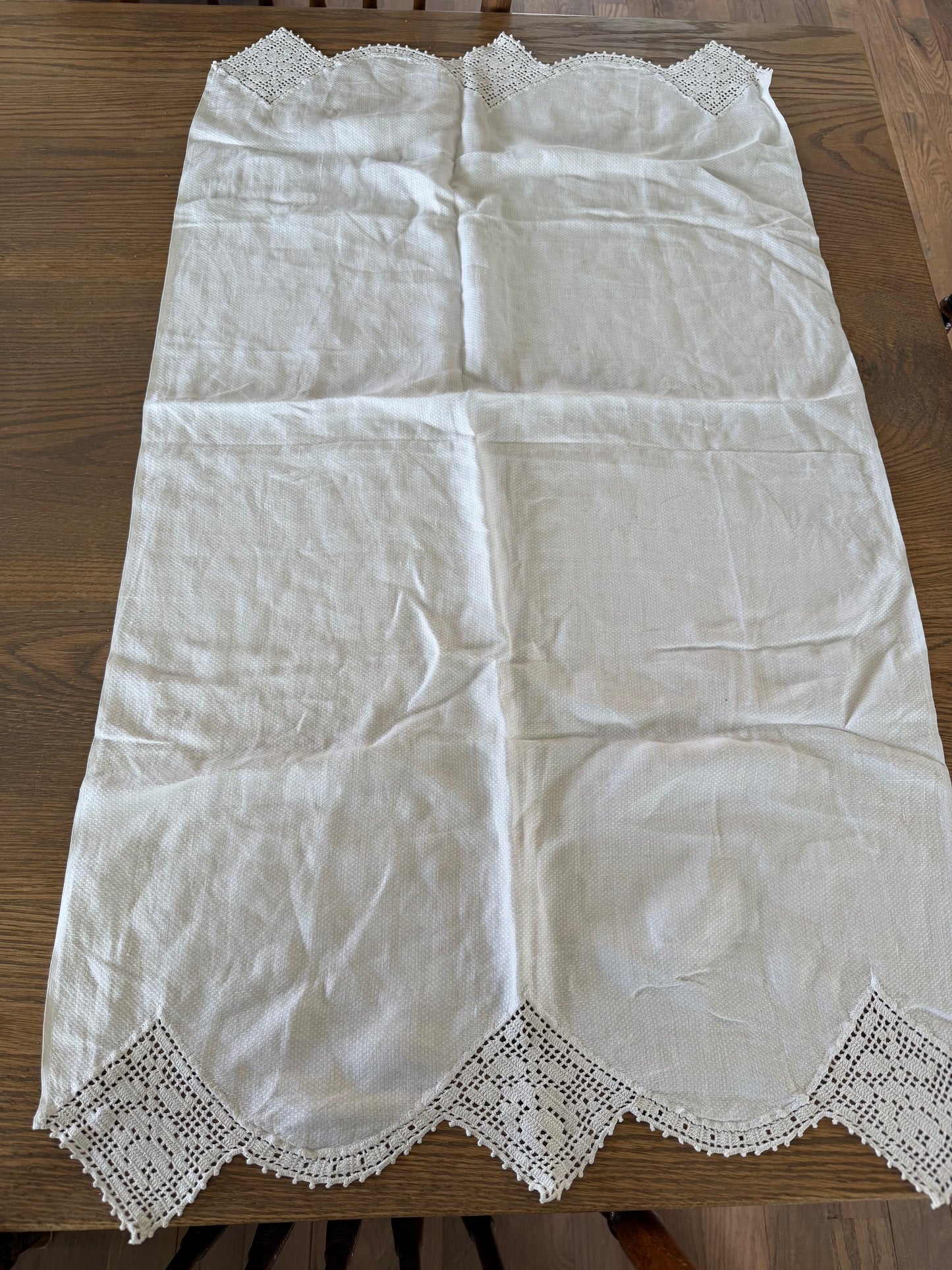 Vintage white linen table runner featuring hand-crocheted lace borders.