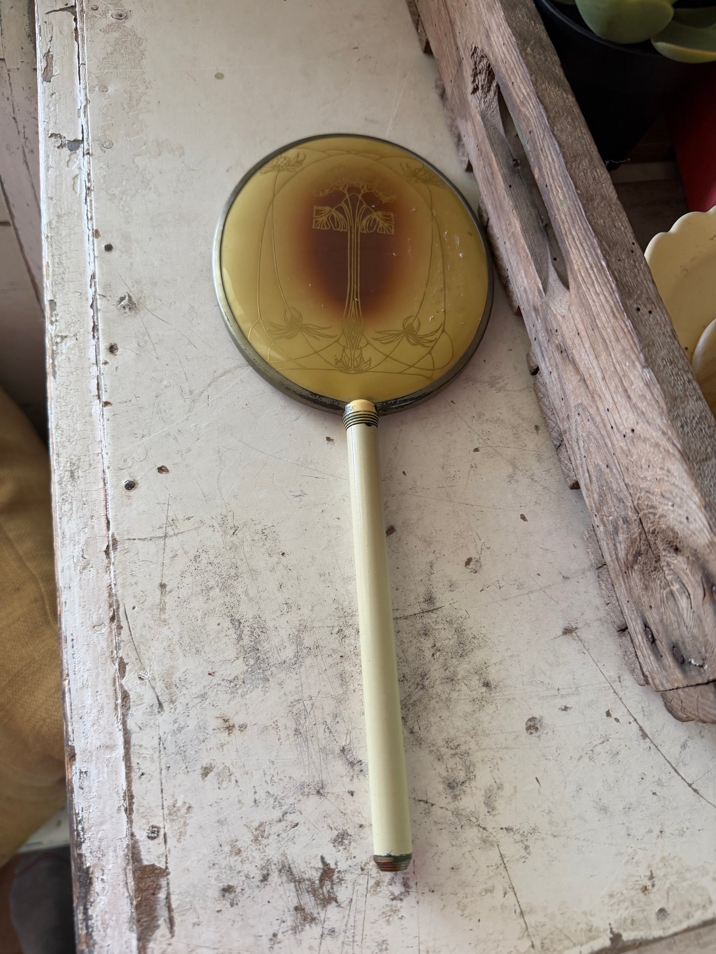 Art Nouveau style hand mirror with a yellow celluloid back and a long, slender handle