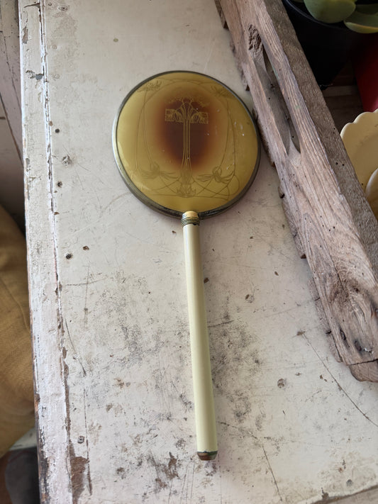 Art Nouveau style hand mirror with a yellow celluloid back and a long, slender handle