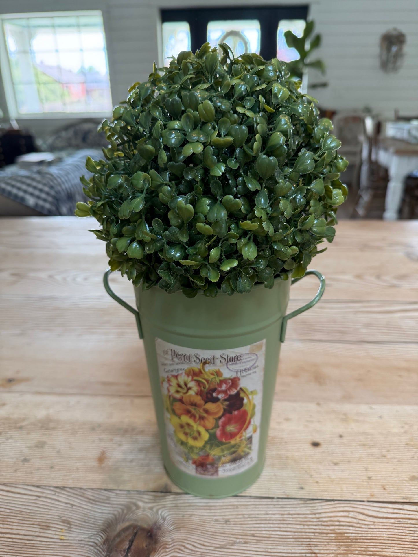 Artificial boxwood topiary in painted metal flower bucket
