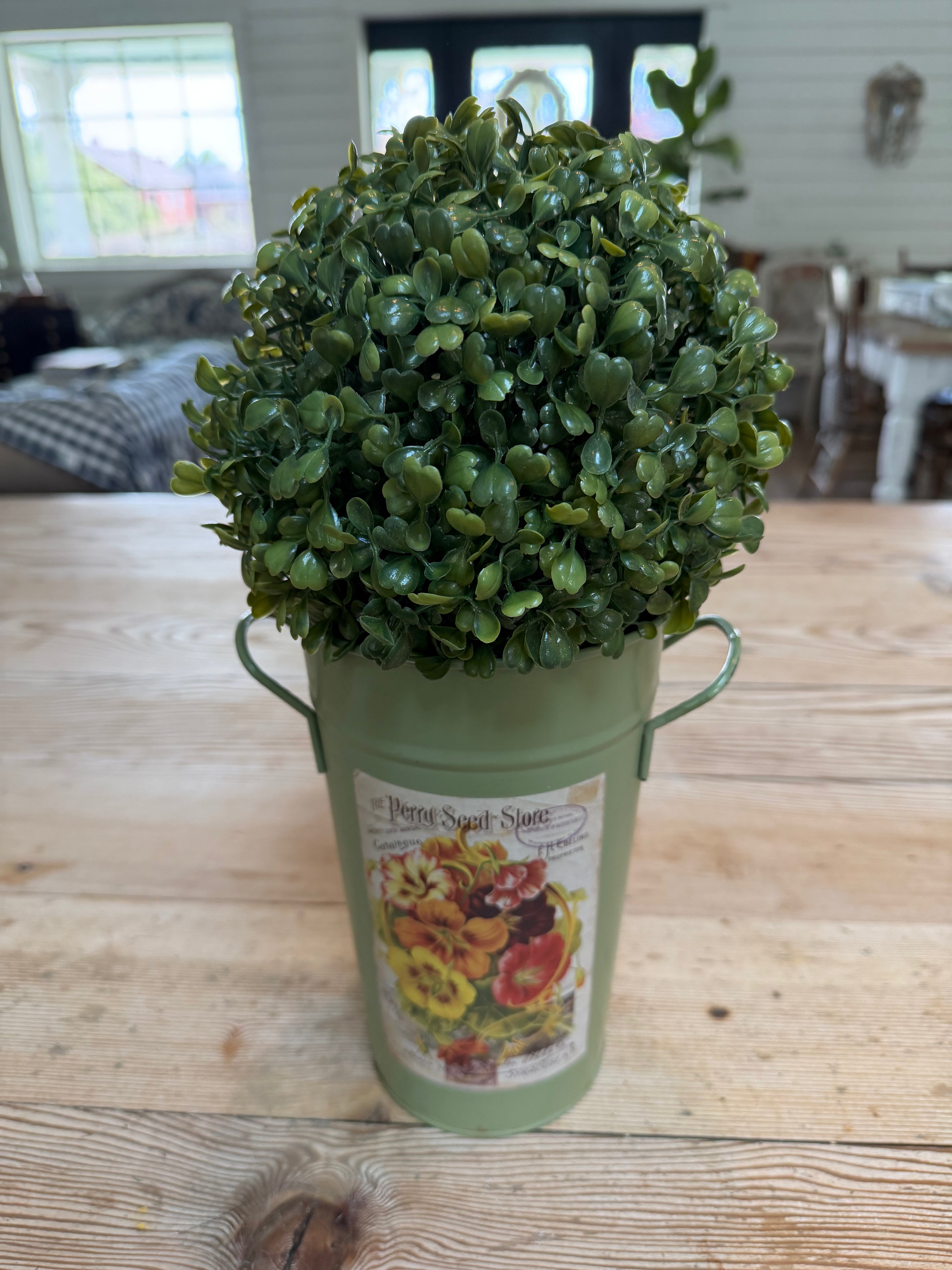Artificial boxwood topiary in painted metal flower bucket