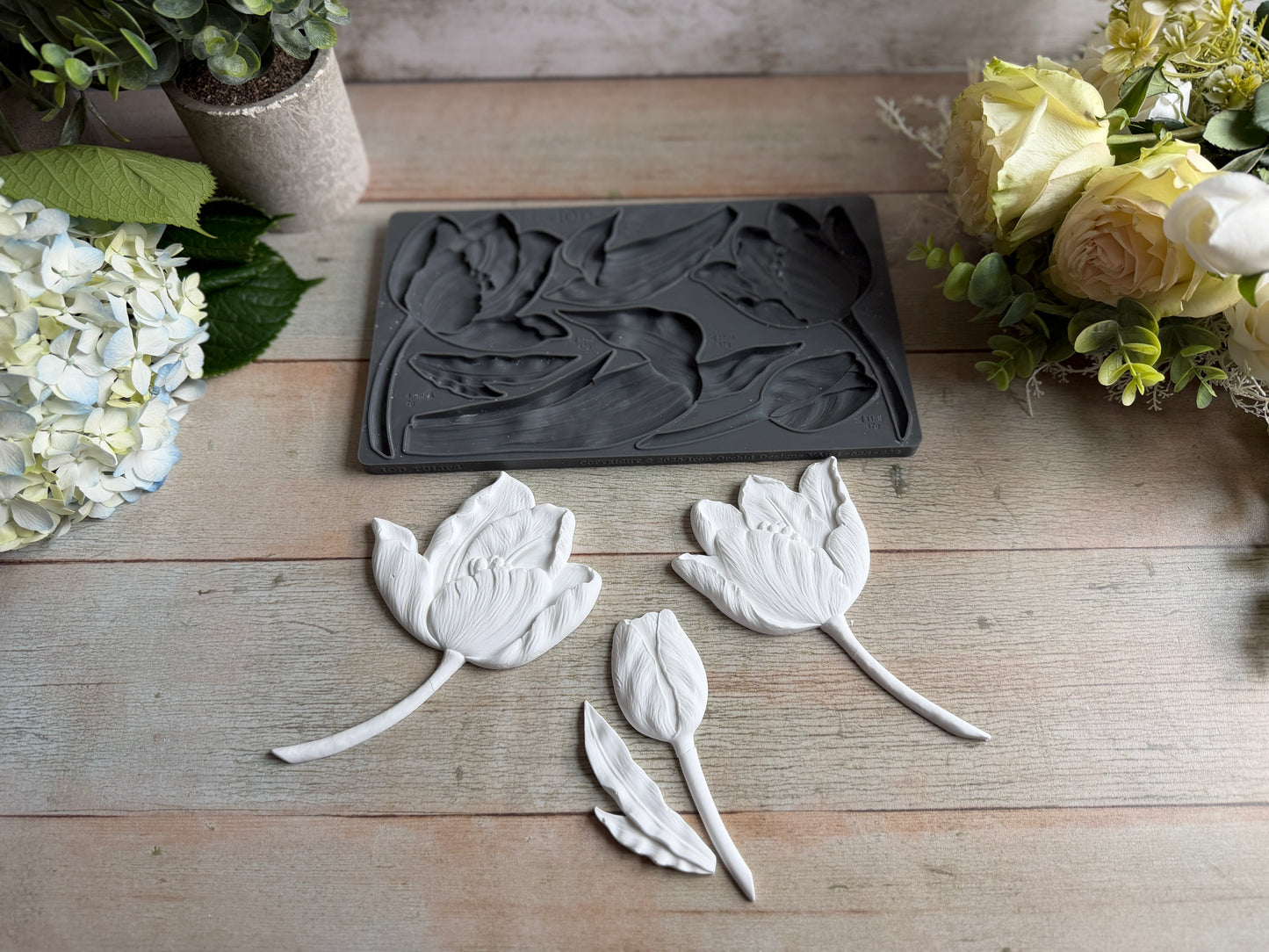 Decorative leaf-shaped molds on a wooden surface with floral decorations.