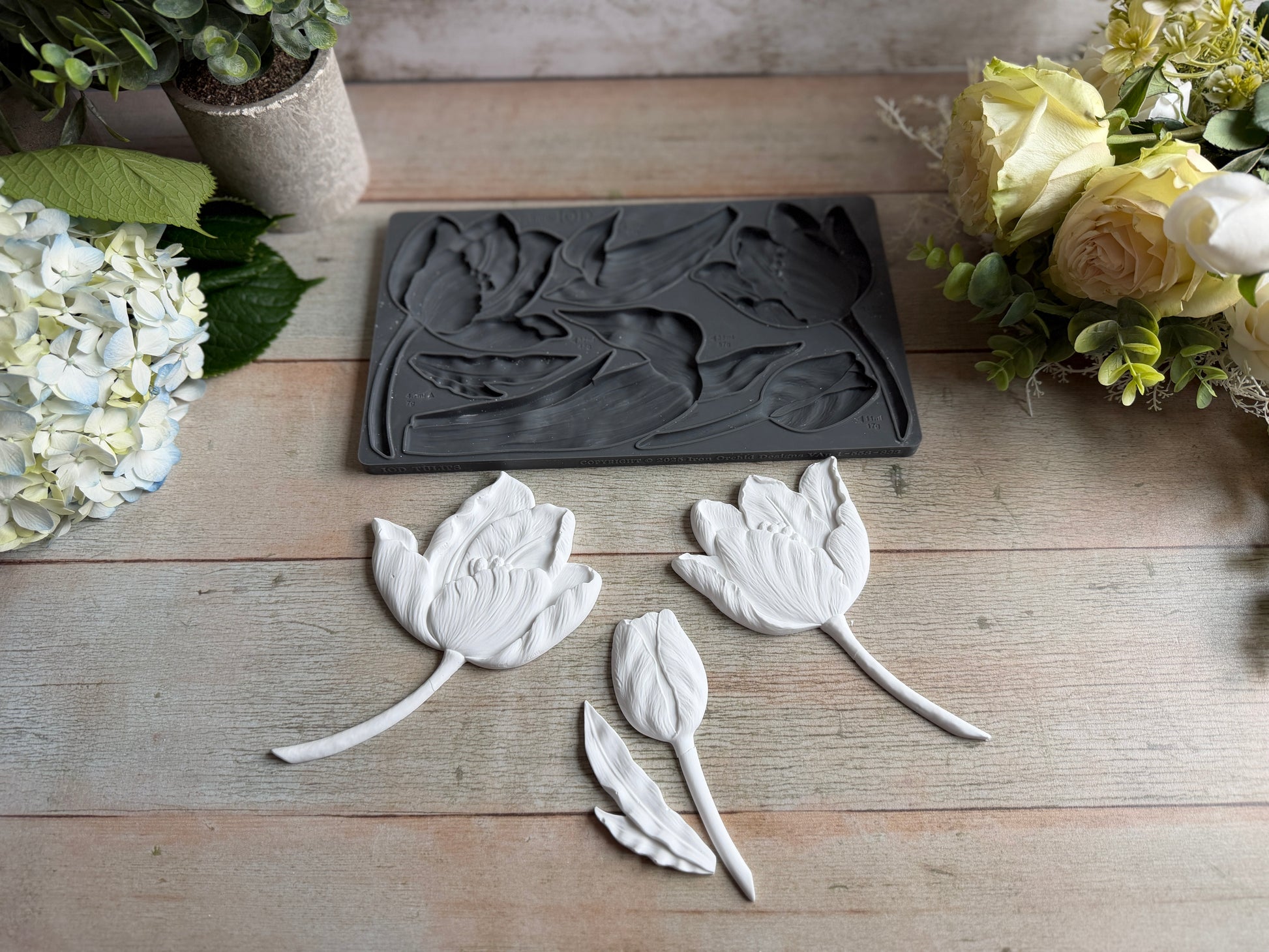 Decorative leaf-shaped molds on a wooden surface with floral decorations.